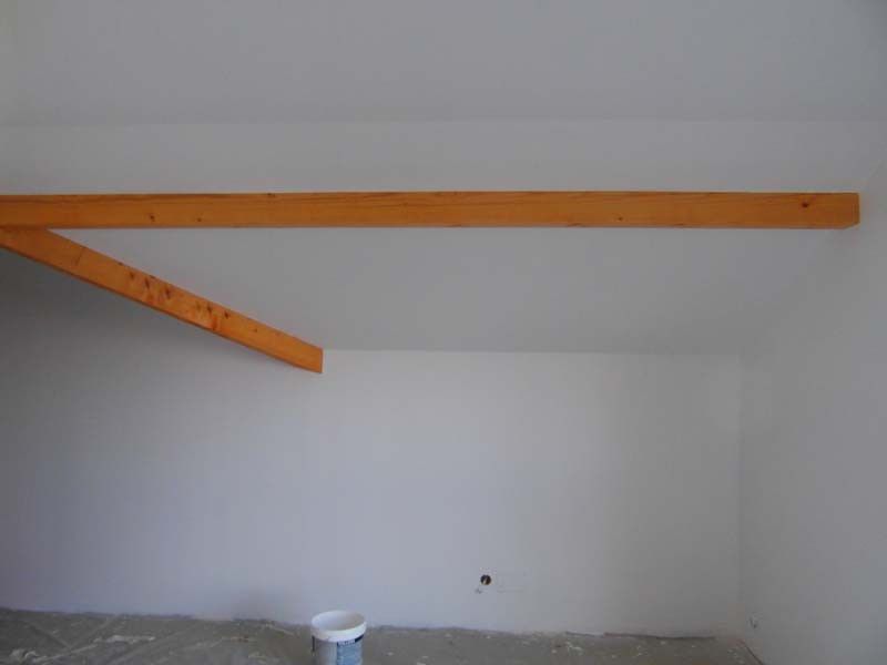 Application de peinture blanche sur mur sous comble avec poutres en bois apparentes – Travaux de peinture intérieure AK Rénovation dans le Pays de Gex